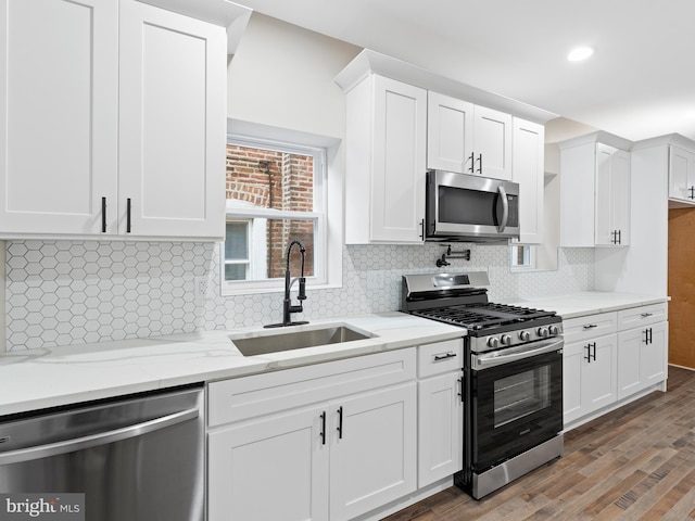 kitchen featuring appliances with stainless steel finishes, tasteful backsplash, sink, white cabinets, and light stone countertops