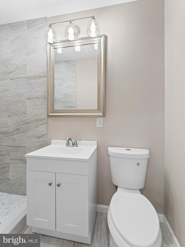 bathroom featuring vanity, toilet, and a tile shower