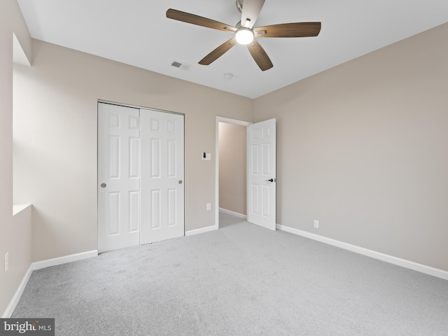 unfurnished bedroom featuring light colored carpet, a closet, and ceiling fan