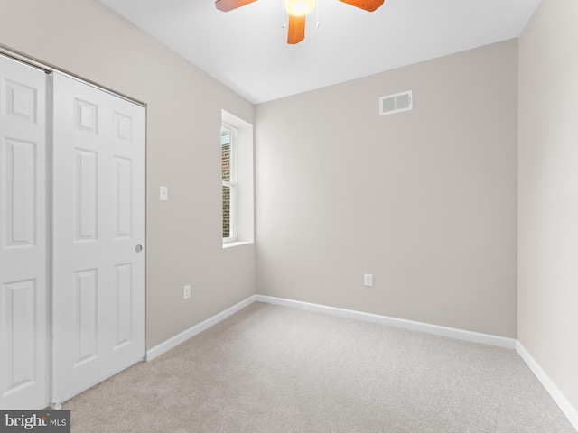 unfurnished bedroom featuring light colored carpet, ceiling fan, and a closet