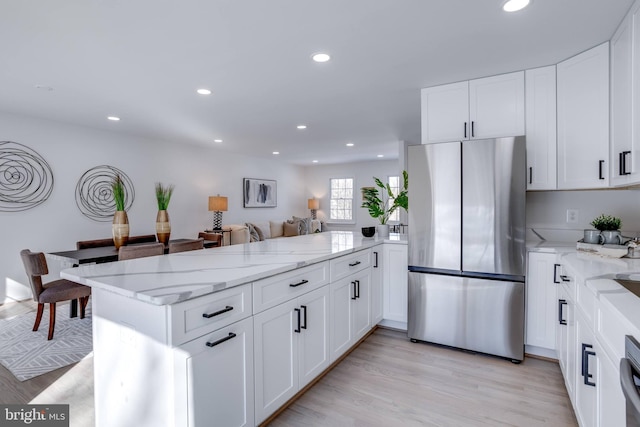 kitchen featuring stainless steel refrigerator, white cabinetry, kitchen peninsula, and light hardwood / wood-style floors