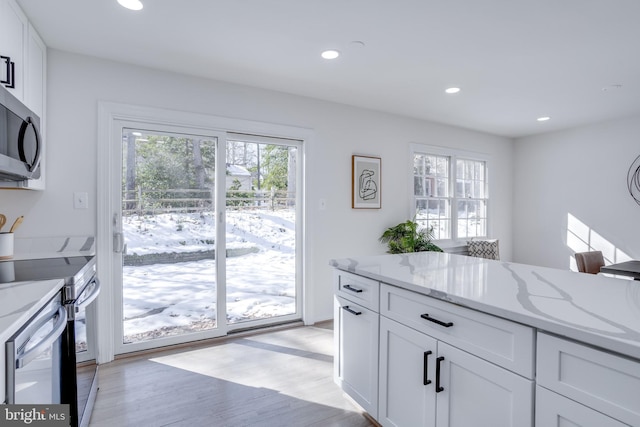 kitchen featuring range with electric stovetop, light wood-type flooring, white cabinets, and light stone counters