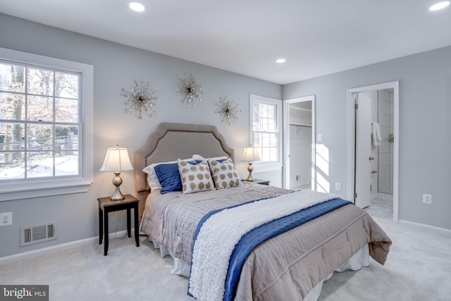 bedroom featuring a walk in closet, light colored carpet, and connected bathroom