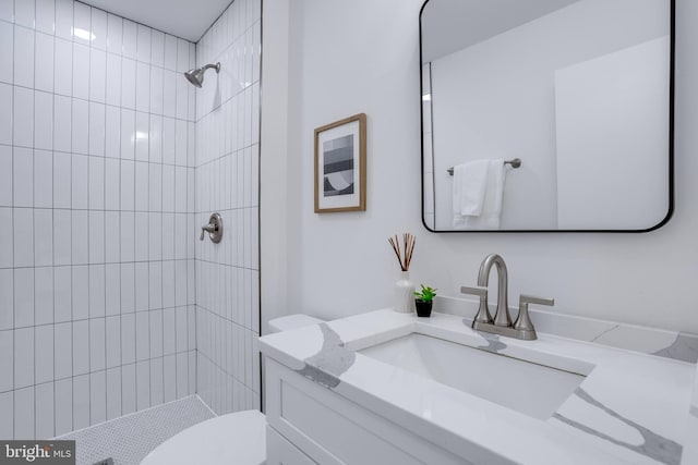 bathroom featuring vanity, toilet, and a tile shower