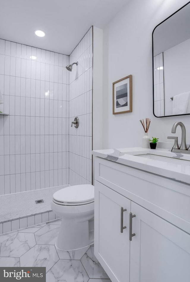 bathroom with vanity, tiled shower, and toilet