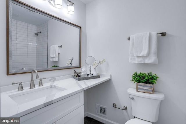 bathroom with vanity, tiled shower, and toilet