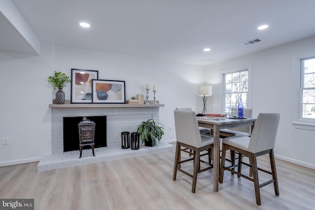 dining area with a wood stove and light hardwood / wood-style flooring