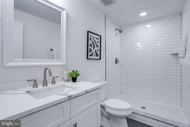 bathroom featuring vanity, toilet, and a tile shower