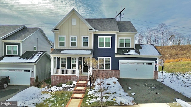 craftsman-style home with a porch, aphalt driveway, board and batten siding, and brick siding