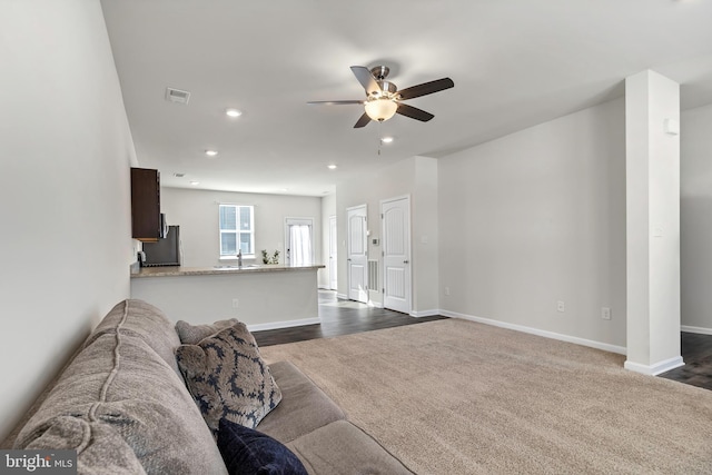 living room with ceiling fan, sink, and dark colored carpet