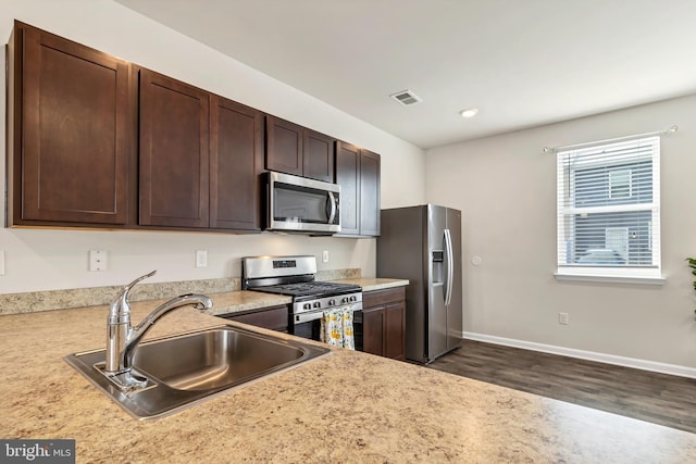 kitchen featuring dark brown cabinetry, sink, dark wood-type flooring, and appliances with stainless steel finishes