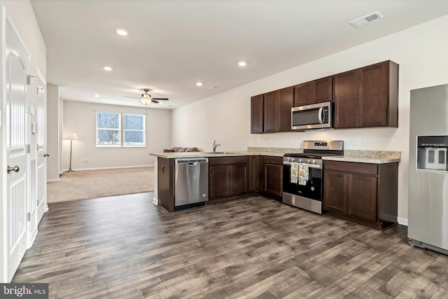 kitchen with sink, dark brown cabinets, stainless steel appliances, dark hardwood / wood-style flooring, and kitchen peninsula