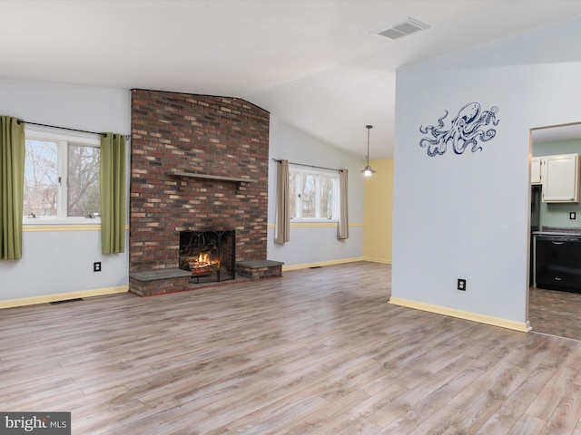 unfurnished living room with lofted ceiling, a fireplace, and light wood-type flooring