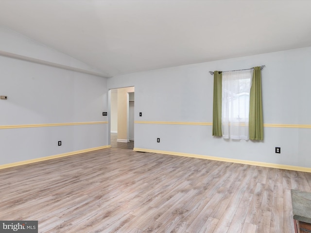 empty room featuring vaulted ceiling and light wood-type flooring