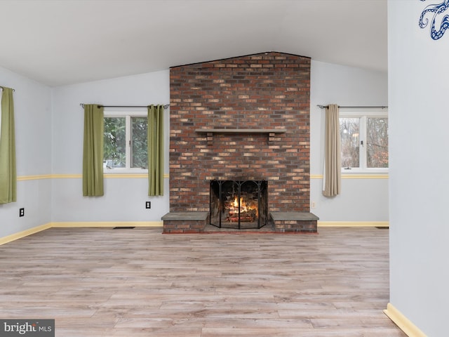 unfurnished living room featuring lofted ceiling, a fireplace, and light wood-type flooring