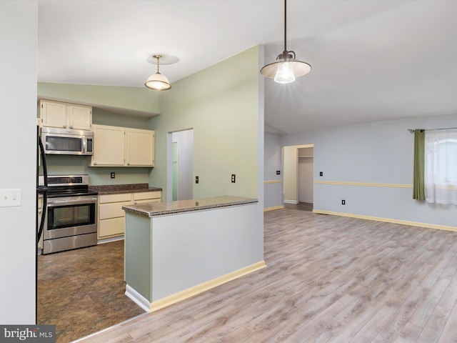 kitchen featuring decorative light fixtures, light wood-type flooring, vaulted ceiling, and appliances with stainless steel finishes