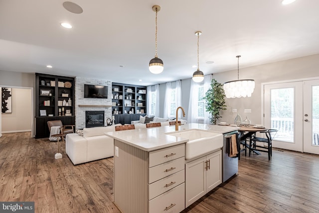 kitchen featuring sink, decorative light fixtures, built in features, and an island with sink