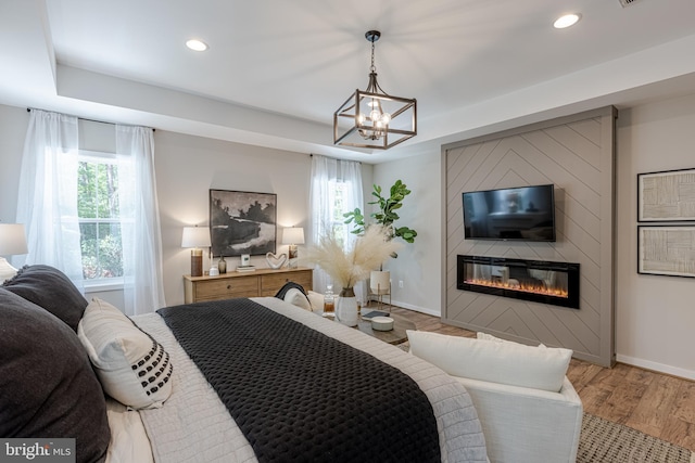 bedroom featuring hardwood / wood-style floors, a tray ceiling, and a fireplace