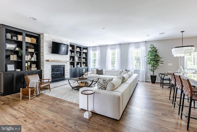 living room with a fireplace, built in shelves, and wood-type flooring