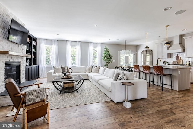 living room featuring sink, a fireplace, dark hardwood / wood-style floors, and a healthy amount of sunlight