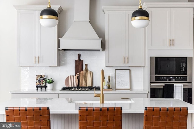 kitchen featuring premium range hood, appliances with stainless steel finishes, hanging light fixtures, and decorative backsplash