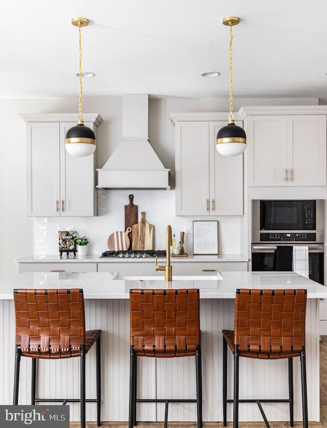 kitchen featuring custom exhaust hood, a breakfast bar, and appliances with stainless steel finishes