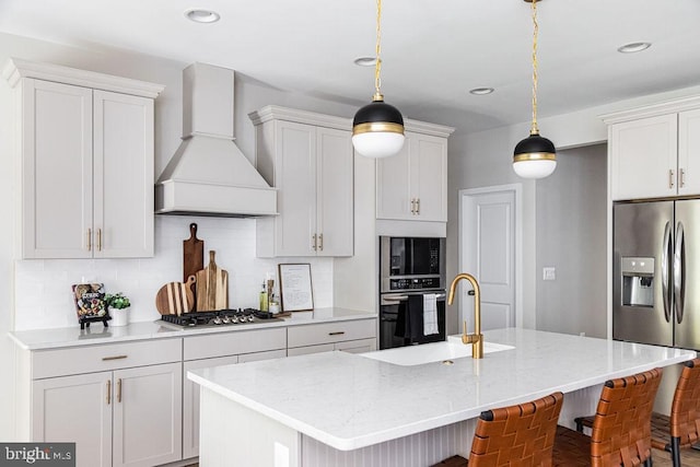 kitchen with stainless steel appliances, hanging light fixtures, custom range hood, and a center island with sink