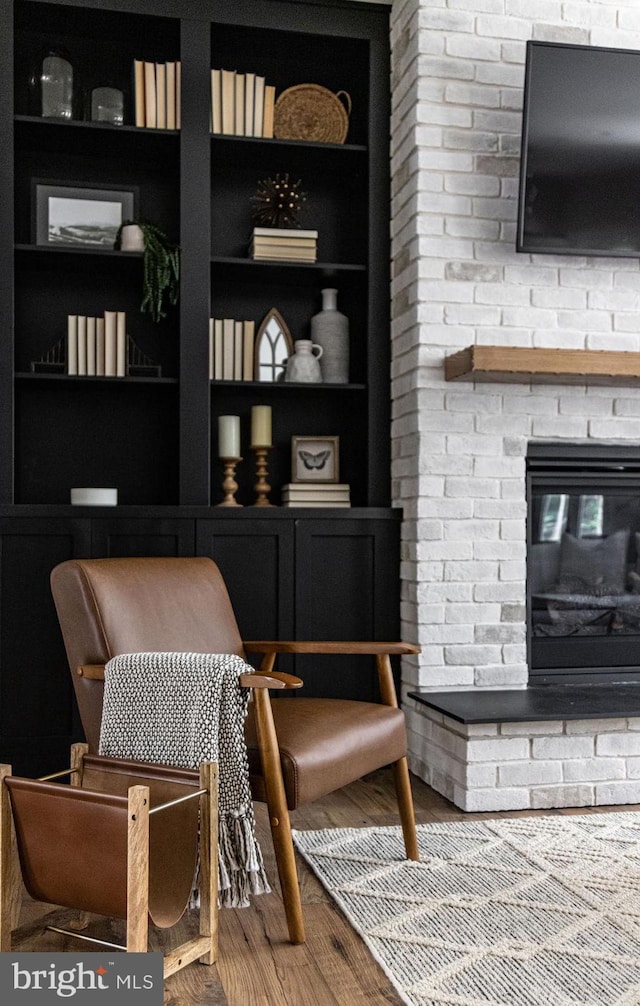 living area with built in shelves, a fireplace, and wood-type flooring