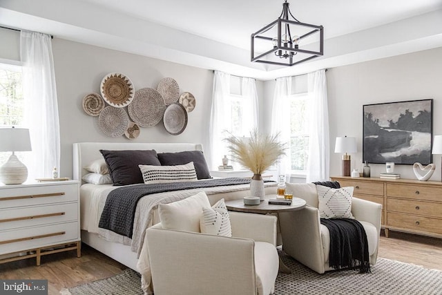 bedroom with multiple windows, wood-type flooring, and an inviting chandelier