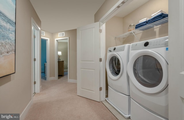 laundry room with separate washer and dryer and light carpet