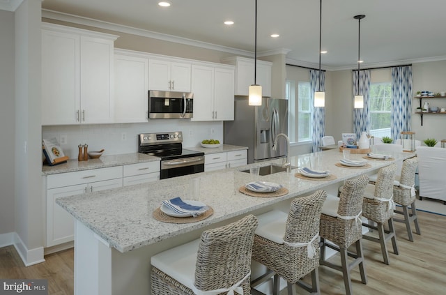 kitchen with appliances with stainless steel finishes, a center island with sink, and white cabinets