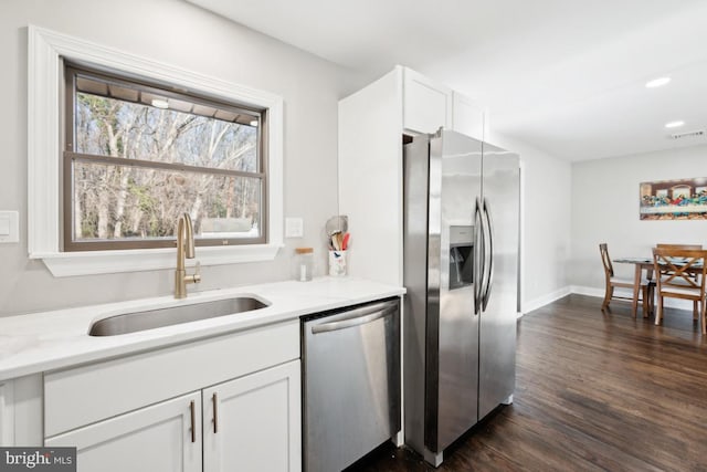 kitchen with sink, dark hardwood / wood-style flooring, stainless steel appliances, light stone countertops, and white cabinets