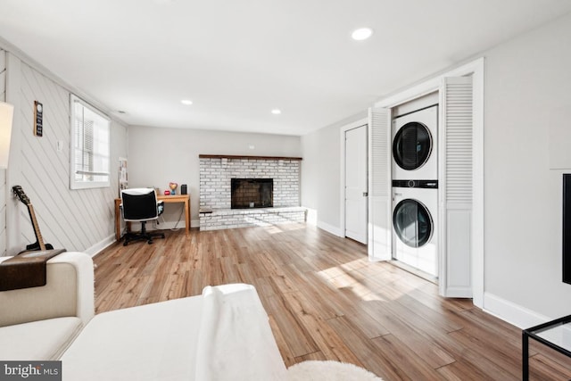 living room with stacked washer and clothes dryer, a fireplace, and light hardwood / wood-style floors