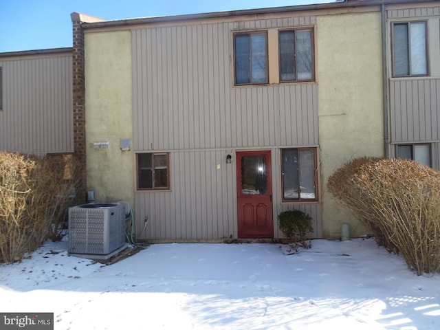 snow covered house featuring cooling unit