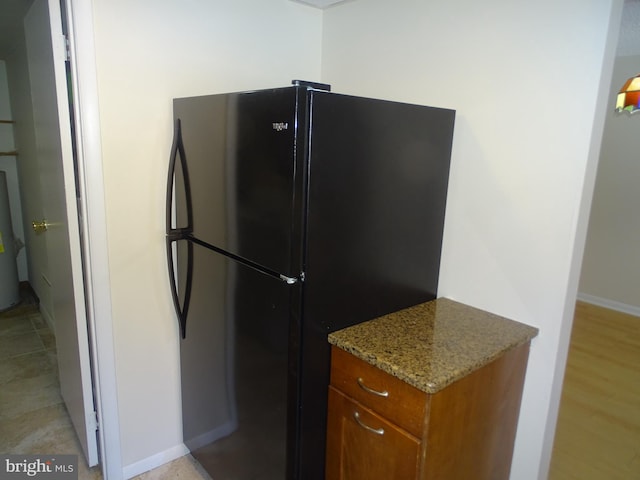 kitchen with light stone countertops and black fridge