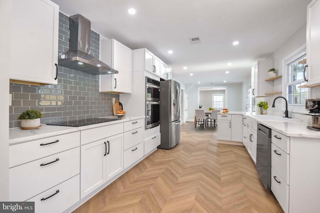 kitchen with sink, white cabinetry, appliances with stainless steel finishes, kitchen peninsula, and wall chimney range hood