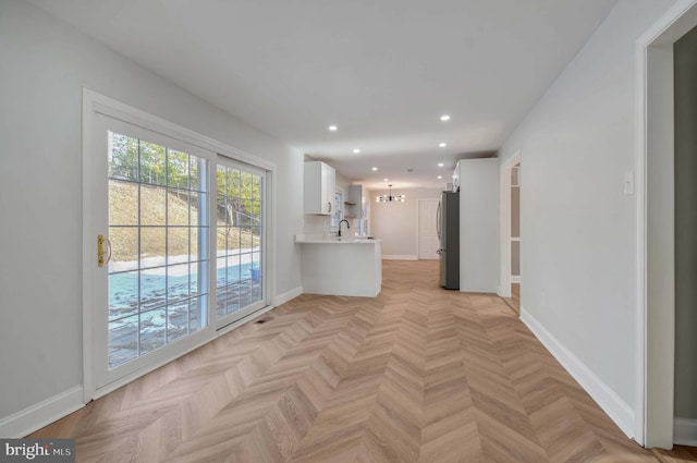 unfurnished living room featuring a chandelier, sink, and light parquet floors