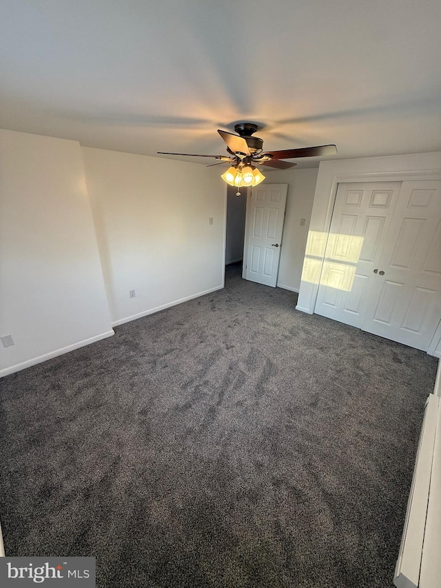 unfurnished bedroom with ceiling fan and dark colored carpet