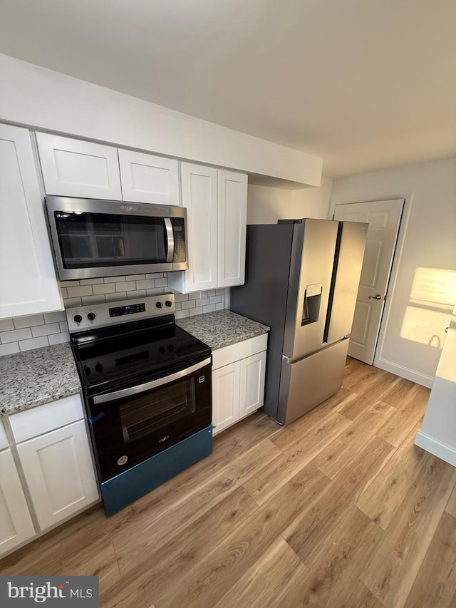 kitchen featuring tasteful backsplash, light hardwood / wood-style floors, white cabinets, and appliances with stainless steel finishes