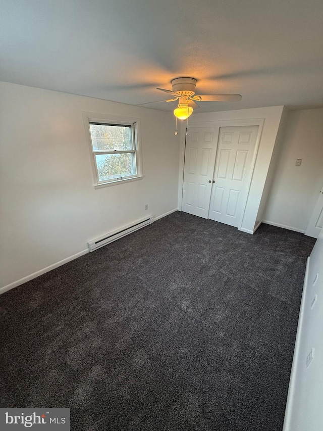 unfurnished bedroom featuring dark carpet, a baseboard radiator, a closet, and ceiling fan