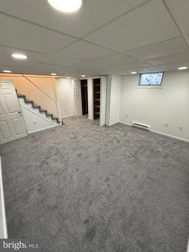 basement featuring carpet flooring, a paneled ceiling, and baseboard heating