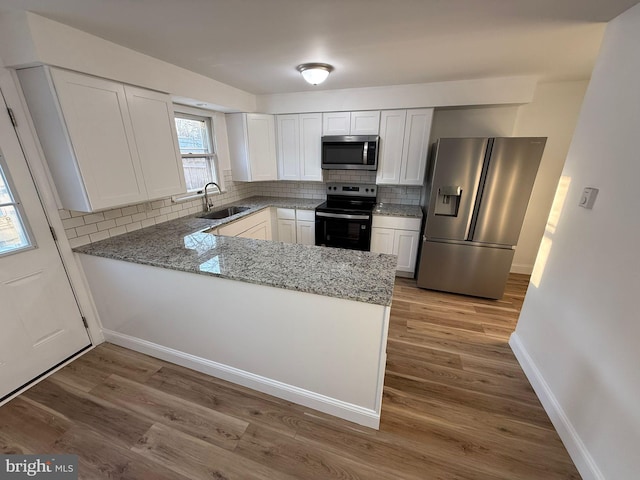 kitchen with appliances with stainless steel finishes, white cabinets, and light stone counters