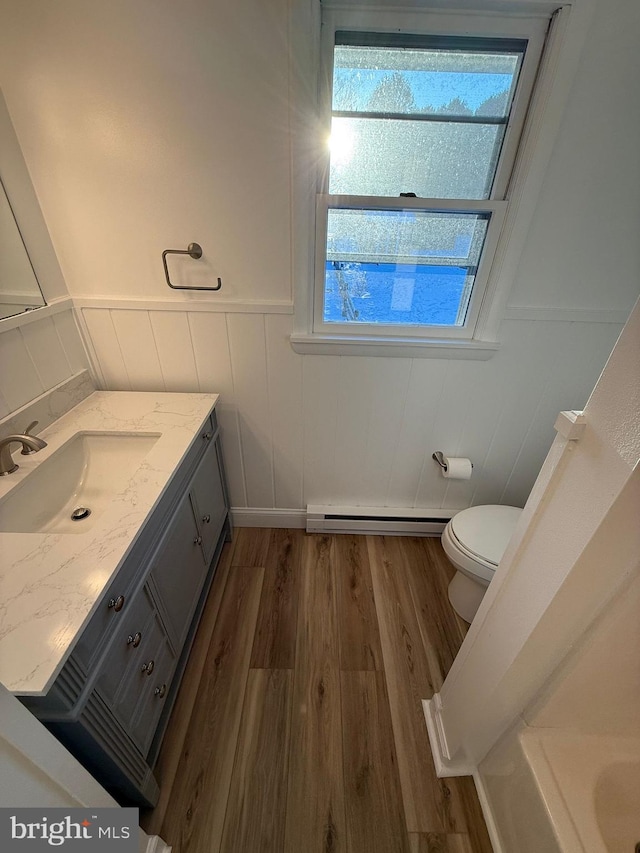 bathroom with vanity, hardwood / wood-style floors, a baseboard radiator, and toilet