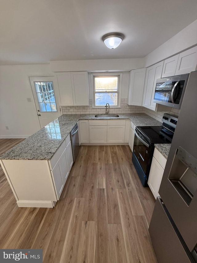 kitchen with white cabinetry, sink, light stone counters, and stainless steel appliances