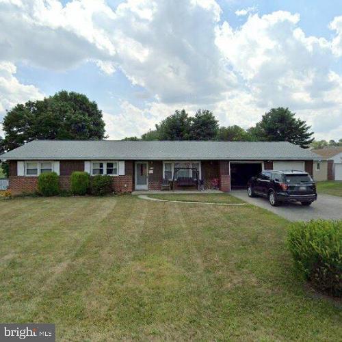 single story home featuring driveway, a front lawn, and an attached garage