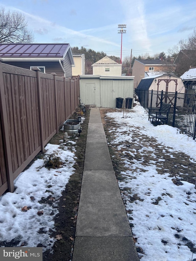 yard layered in snow featuring a storage unit