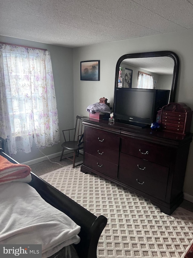 bedroom with multiple windows, light carpet, and a textured ceiling