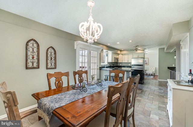 dining area with sink, ceiling fan with notable chandelier, a textured ceiling, and french doors