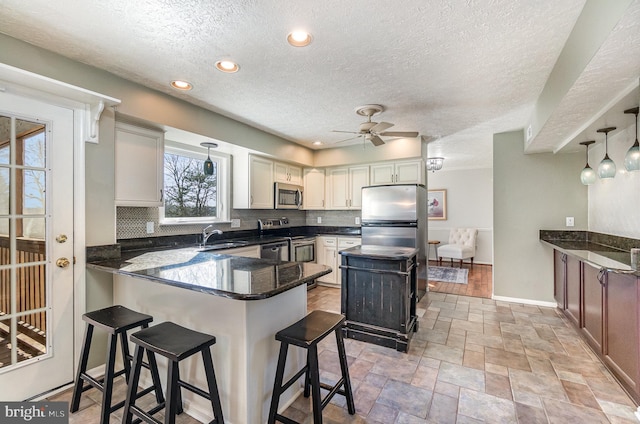 kitchen featuring pendant lighting, a breakfast bar, backsplash, stainless steel appliances, and kitchen peninsula