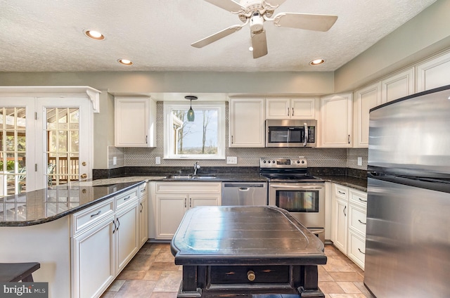 kitchen with white cabinetry, appliances with stainless steel finishes, sink, and decorative light fixtures